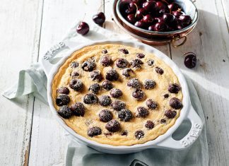 Cherry Clafoutis Cherry Clafoutis on white wood in white Staub cast iron