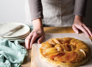 Origin of A Classic: Tarte Tatin Origin of A Classic: Tarte Tatin on parchment with hands about to cut into tart