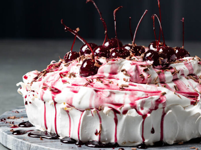 pavlova topped with cream and cherries