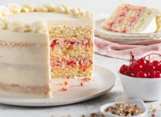 Cherry-Pecan Cake cherry-pecan cake on a serving plate with a slice of cake on another plate and a bowl of cherries and a bowl of pecans