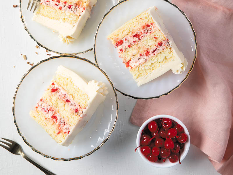 slices of cherry pecan cake on individual plates with a bowl of cherries