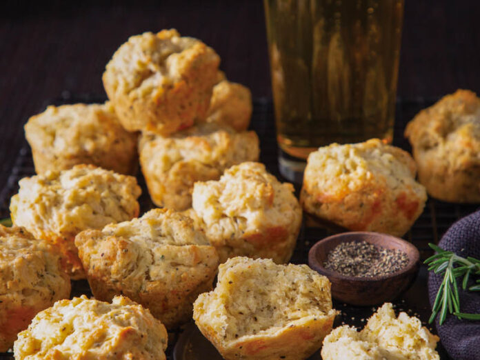 beer-cheddar muffins in a stack next to a tall glass of lager
