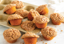 Pumpkin Snickerdoodle Muffins Snickerdoodle Pumpkin Muffins in GoldTouch muffin tin scattered on white surface.