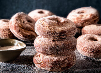 Spiced Apple Cider Doughnuts Spiced apple cider doughnuts on dark surface with cinnamon sugar spread