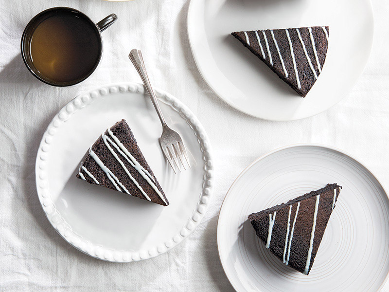 Flourless Black Cocoa with Coconut Glaze sliced on white plates