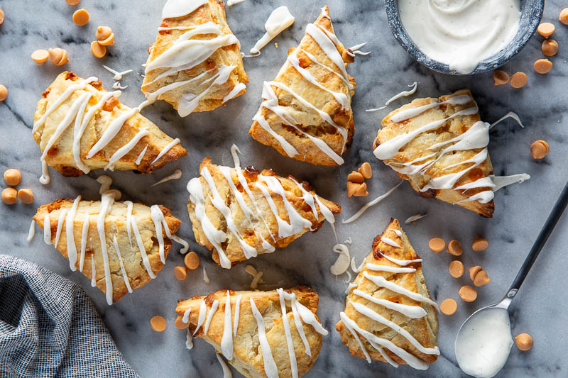 Butterscotch Scones with Vanilla Bean Glaze on white surface with glaze drizzled on top.
