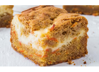 Our Best Carrot Cake Recipes Carrot Cake Cheesecake Bars on white cutting board with carrots