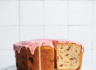Roasted Strawberry Pound Cake Roasted Strawberry Pound Cake on white cake stand with one slice of cake on white plate and jar of strawberry jam with spoon and whole strawberries