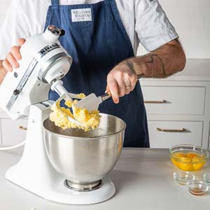 Mixer with buttercream on paddle and bowl of eggs