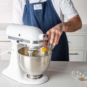 Adding egg into mixing bowl