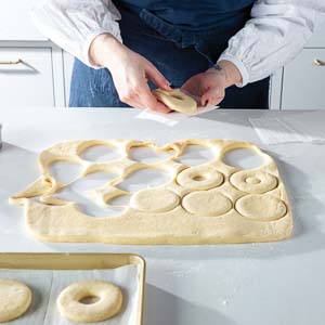 Cutting out doughnuts and putting on baking sheet