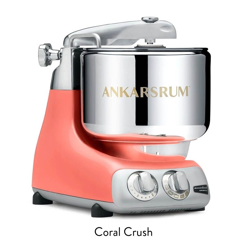 Coral pink stand mixer with a chrome stainless-steel mixing bowl on a white background.
