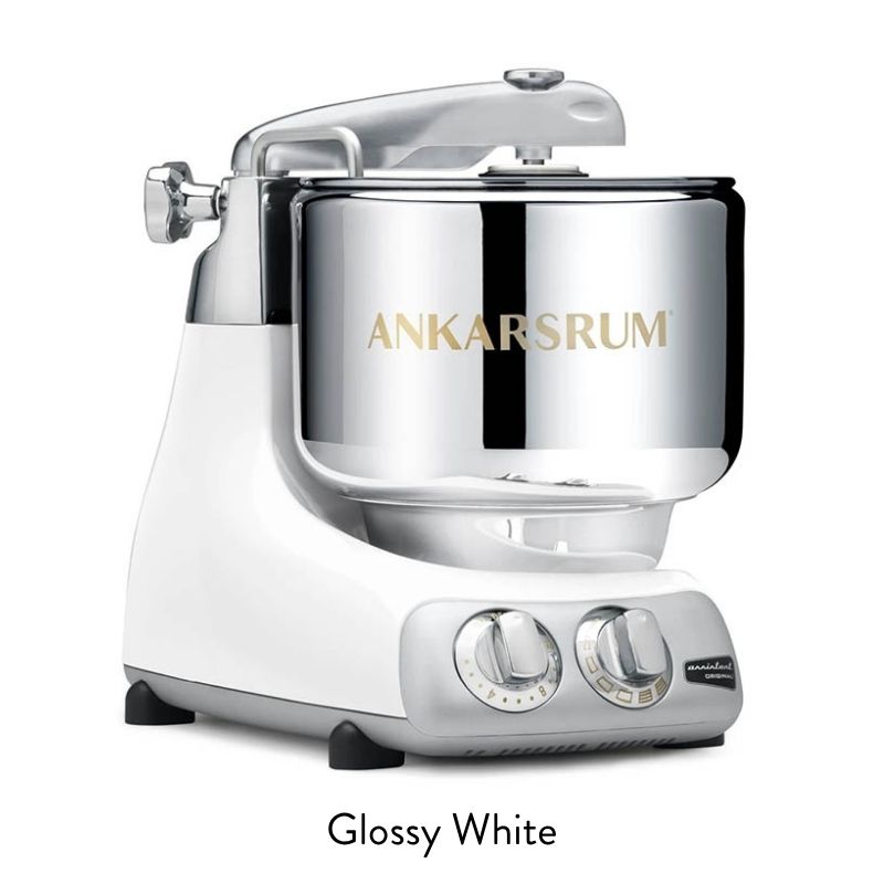 Glossy white Ankarsrum stand mixer with a shiny chrome bowl and dual front dials for speed and mode selection.