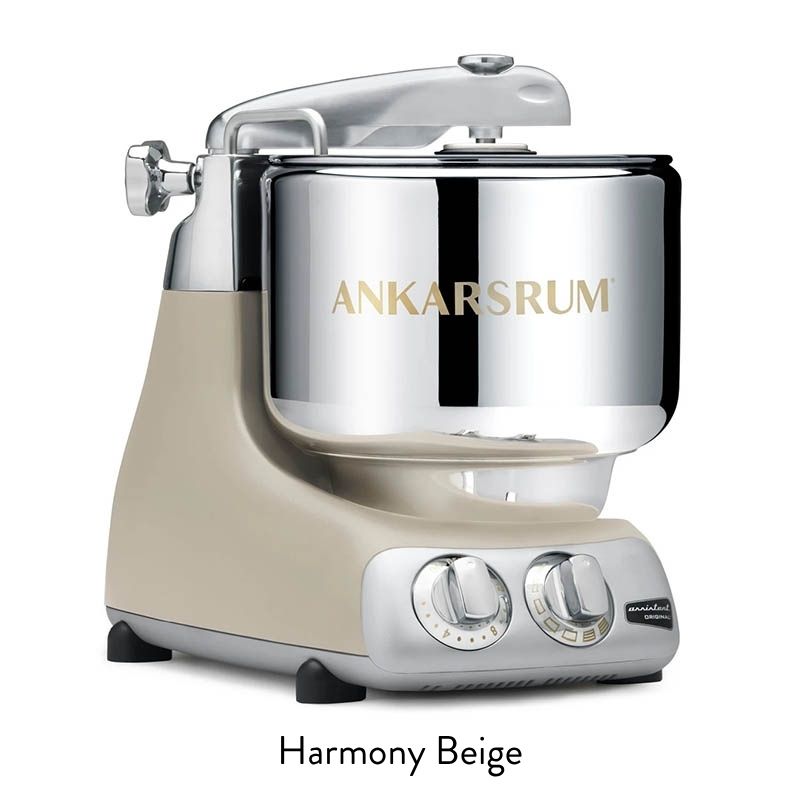Beige and chrome stand mixer on a kitchen counter with two control dials and a metal bowl.