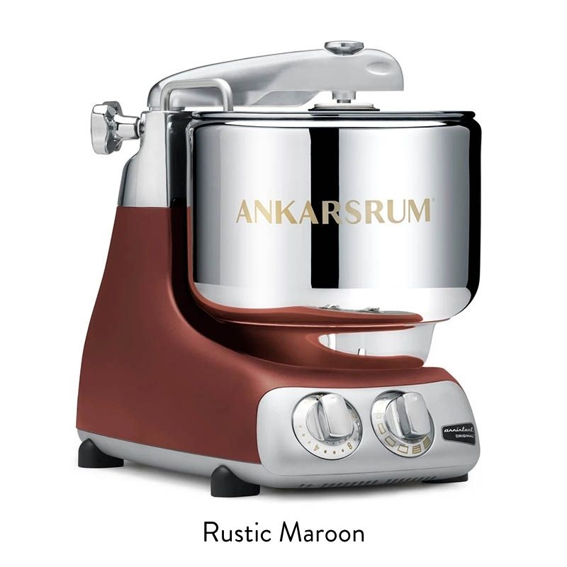 Stand mixer with a shiny chrome mixing bowl and a rustic maroon base, featuring two control dials on the front.