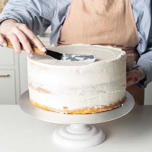 adding buttercream to cake layers