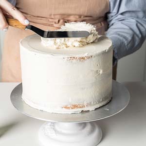 adding buttercream to cake layers