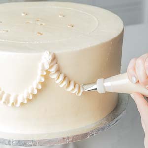 piping decorations onto cake