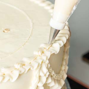 piping decorations onto cake