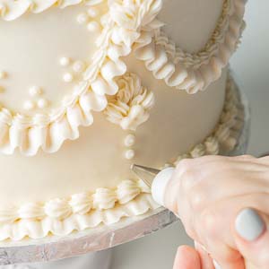piping decorations onto cake