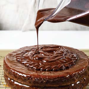 Pouring chocolate glaze on cake layers