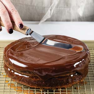 Spreading chocolate glaze on cake layers