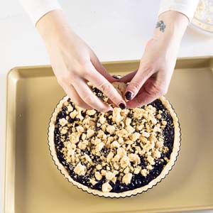 Adding crumble on top of blueberry tart