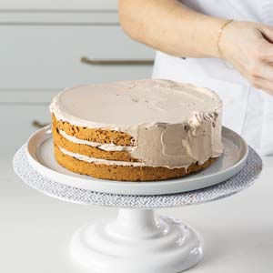 spreading buttercream on outside of cake