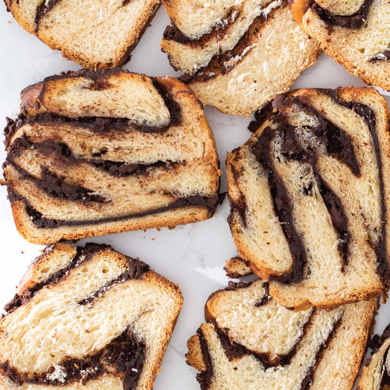 Sliced chocolate babka pieces with swirled filling on a light background.
