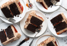 Chocolate PB&J Cake Slices of chocolate layer cake with dark frosting and a red jam filling on white plates, with forks nearby.