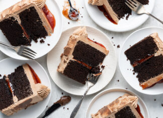Chocolate PB&J Cake Slices of chocolate layer cake with dark frosting and a red jam filling on white plates, with forks nearby.