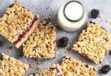 Fast-Fix Baking for Summer Crumbled blackberry bars scattered on a gray surface with a small pitcher of milk and fresh blackberries nearby.