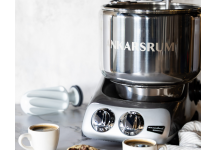Ankarsrum Recipe Conversions Stainless steel Ankarsrum stand mixer on a marble kitchen counter, with coffee cups and cookies nearby.
