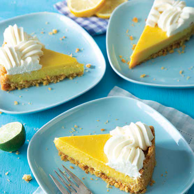 Slices of lemon cheesecake with crumb crust and swirls of whipped cream on blue plates.