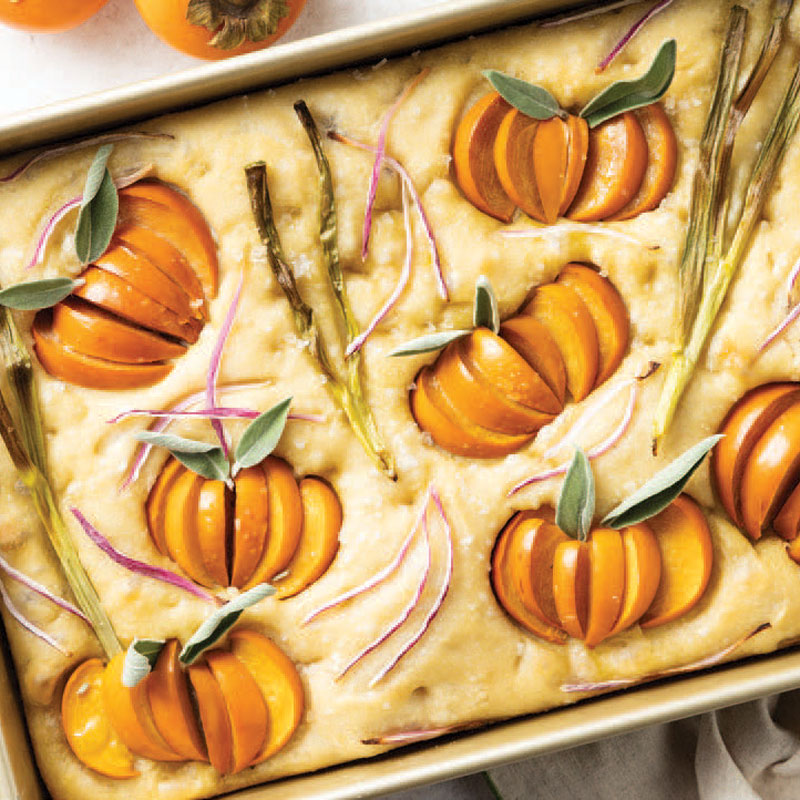 Harvest focaccia topped with orange pumpkin wedges, sage, rosemary, and red onion slivers.