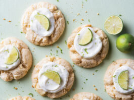 Key Lime Thumbprint Cookies Cakes or cookies topped with white frosting and lime wedges on a pale green background, arranged in a scattered pattern