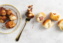 Dinner Roll Dough Top-down view of a white plate with golden fried chicken bites, a fork, and several bread rolls on a light textured surface.