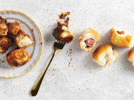 Dinner Roll Dough Top-down view of a white plate with golden fried chicken bites, a fork, and several bread rolls on a light textured surface.