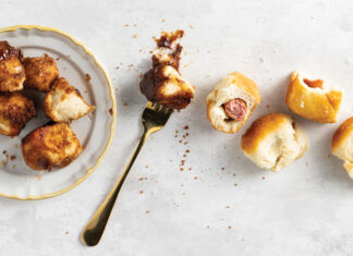 Dinner Roll Dough Top-down view of a white plate with golden fried chicken bites, a fork, and several bread rolls on a light textured surface.