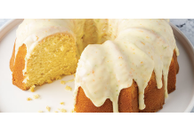 Citrus Pound Cake Lemon Bundt cake with white glaze, sliced to reveal a light yellow crumb; citrus fruits and a grater visible in the background.