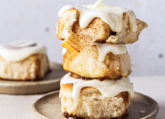 Brian’s Cinnamon Rolls (the Sourdough Version) Stack of three thick scones with white glaze dripping from a spoon above them, ready for dessert.