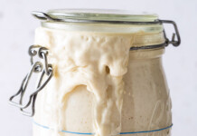 Make it Sourdough Mason jar of sourdough starter overflowing with foamy, pale batter on the rim and down the side.