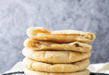 Pocket Pita Bread Stack of round flatbreads resting on a black cooling rack in a kitchen.