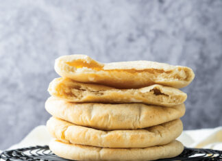 Pocket Pita Bread Stack of round flatbreads resting on a black cooling rack in a kitchen.