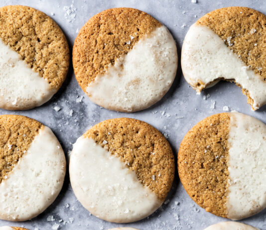 Salted Maple Espresso Cookies Row of round cookies with half white icing on a cool gray marble surface