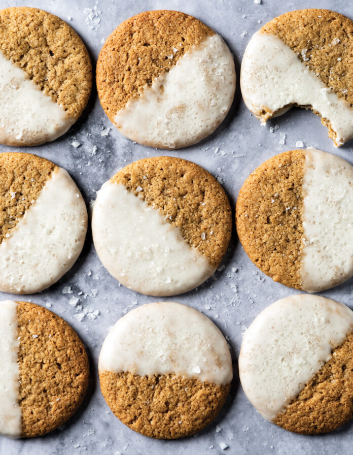 Salted Maple Espresso Close002KG Row of round cookies with half white icing on a cool gray marble surface