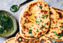 Naan Golden flatbreads topped with chopped herbs, garlic, and a drizzle of oil, served with a herb vinaigrette on the side.