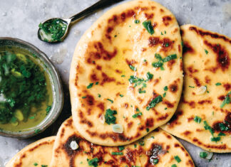 Naan Golden flatbreads topped with chopped herbs, garlic, and a drizzle of oil, served with a herb vinaigrette on the side.